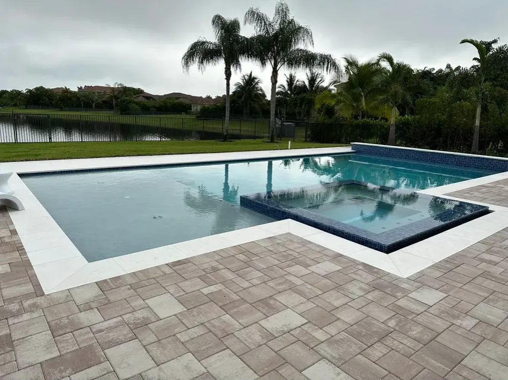 Custom geometric pool with a raised spillover spa and large-format paver deck built by SFC Pool Corp in Port Charlotte, Florida