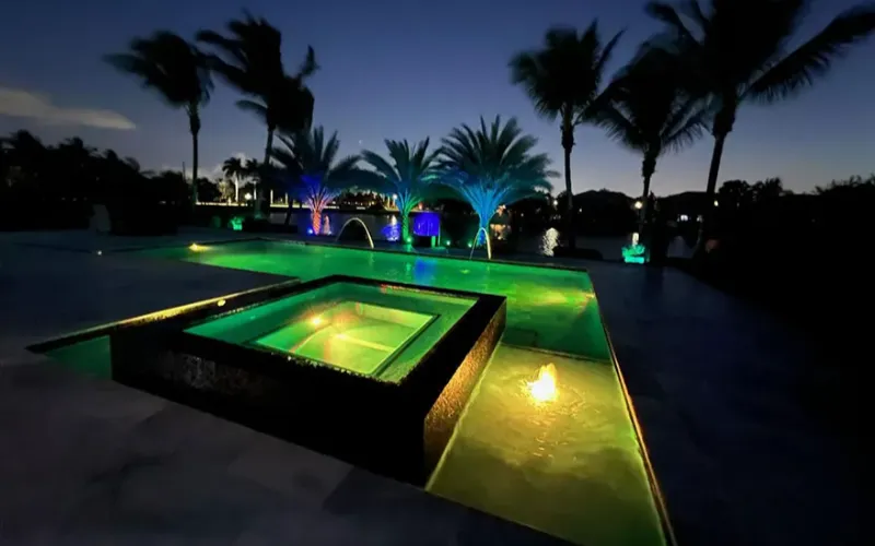 Raised spa lit with color-changing LED lighting at night in a Southwest Florida backyard built by SFC Pool Corp